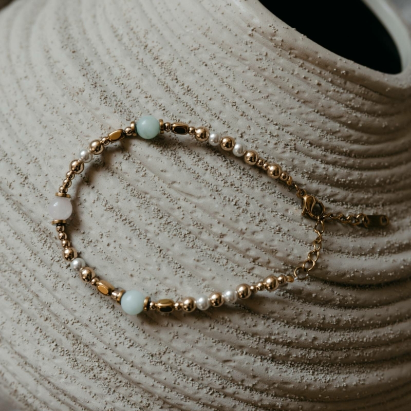 Bransoletka z pereł, amazonitu i kwarcu różowego na tle glinianego wazonu w naturalnych beżowych kolorach ziemi